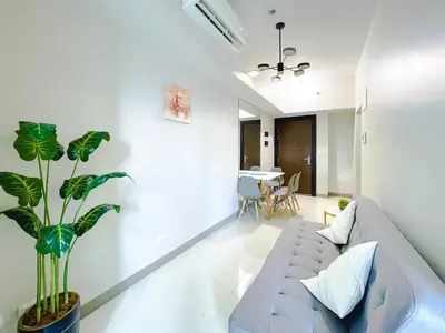 a living room with a couch and a plant at 1 BR Cozy unit Uptown Parksuites BGC in Manila