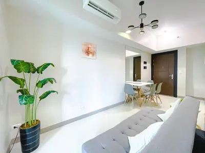 a living room with a couch and a potted plant at 1 BR Cozy unit Uptown Parksuites BGC in Manila
