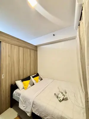 a bedroom with a large white bed with yellow pillows at Relaxing City Retreat in Manila