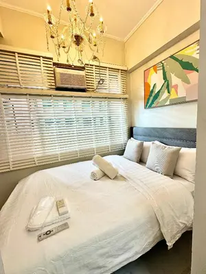 a bedroom with a large white bed with a chandelier at Studio Two Condominium - Olive in Manila
