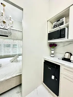a white kitchen with a microwave and a stove at Studio Two Condominium - Olive in Manila