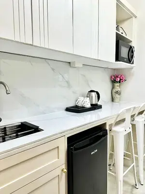 a kitchen with white cabinets and a black dishwasher at Studio Two Condominium - Olive in Manila