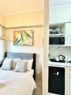a small bedroom with a bed and a kitchen at Studio Two Condominium - Olive in Manila