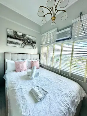 a bedroom with a large white bed with pink pillows at Studio Two Condominium - Olive in Manila