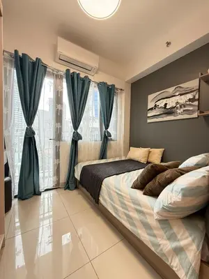 a bedroom with a large bed with blue curtains at Relaxing 1BR condo with Pool and Balcony in Makati in Manila
