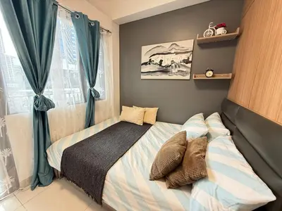 a small bedroom with a bed with blue curtains at Relaxing 1BR condo with Pool and Balcony in Makati in Manila