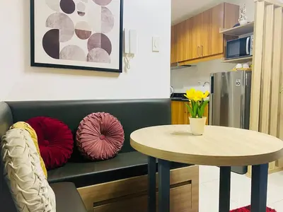 a kitchen with a table and a couch with pillows at Relaxing 1BR condo with Pool and Balcony in Makati in Manila