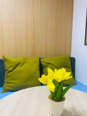 a vase with yellow flowers on a table with two pillows at Relaxing 1BR condo with Pool and Balcony in Makati in Manila