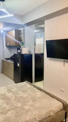 a room with a bed and a television on a wall at Grand View Tower Queen Bed Modern Condo in Manila