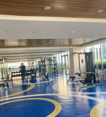 a gym with tread machines and a man standing in the middle at Grand View Tower Queen Bed Modern Condo in Manila