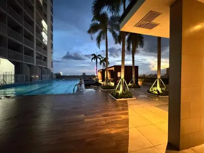 a swimming pool with palm trees and a building at Bay View near US Embassy, Airport in Manila