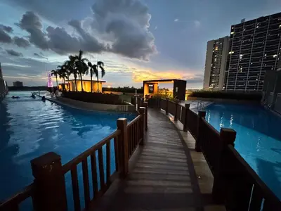 a swimming pool with a wooden walkway next to a building at Bay View near US Embassy, Airport in Manila