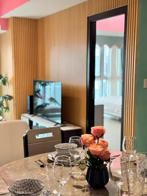 a table with wine glasses and a vase with flowers at Uptown Parksuites Tower 2 4BR in BGC Taguig in Manila