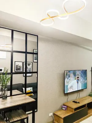 a living room with a television on a wall at Charming 1BR in Uptown Parksuites Tower 2 BGC in Manila