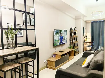 a living room with a couch and a tv on a wall at Charming 1BR in Uptown Parksuites Tower 2 BGC in Manila