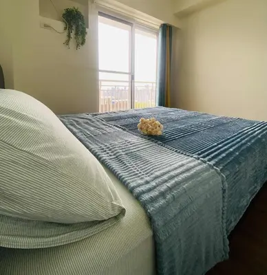 a bedroom with a bed with a blue blanket and a window at V-TAN house in Manila
