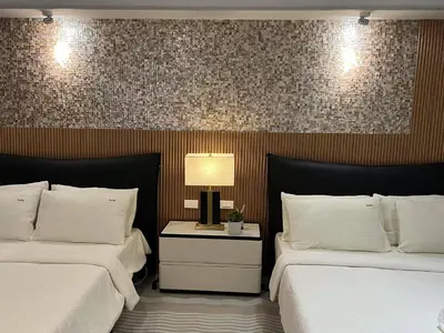 a bedroom with two beds and a table with a lamp at East Glory PentHouse in Manila