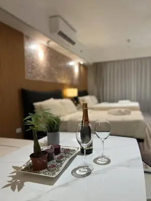 a table with two glasses and a bottle of wine at East Glory PentHouse in Manila