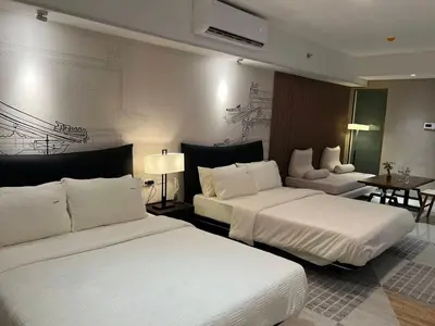 a hotel room with two beds and a table at East Glory PentHouse in Manila