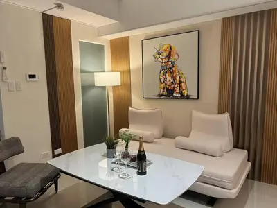 a living room with a white table and a chair at East Glory PentHouse in Manila