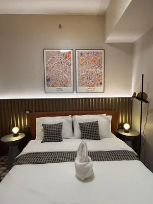 a bedroom with a large bed with two pictures on the wall at Luxury 2BR Condo Retreat Near Airports MOA Okada in Manila
