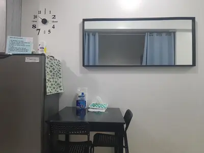 a table with chairs and a mirror on a wall at Cozy Coast Residences Pasay in Manila