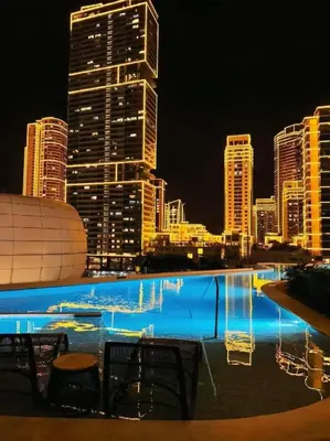 a swimming pool with a city skyline at night at The hotel residences at Acqua in Manila