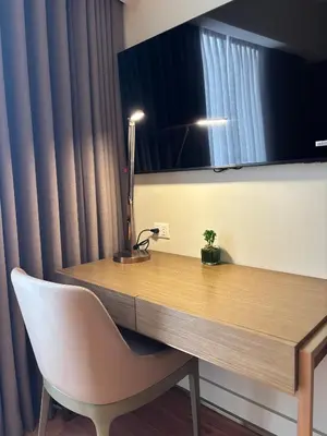 a desk in a room with a chair and a lamp at The hotel residences at Acqua in Manila