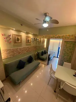 a living room with a blue couch and a table at Sea Residences MOA Oasis-Nicolai Ramos in Manila