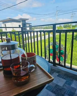 a wooden table with a drink on a balcony at CASA CORAZON Spacious 4BR House Near Tagaytay for Wedding Prep Family Gatherings Reunions and Celebrations Pet Friendly and PWD Accessible in Dagatan