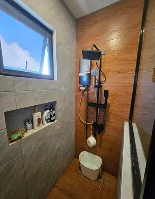 a bathroom with a shower with a toilet and a window at CASA CORAZON Spacious 4BR House Near Tagaytay for Wedding Prep Family Gatherings Reunions and Celebrations Pet Friendly and PWD Accessible in Dagatan