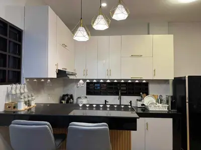 a kitchen with white cabinets and a black counter top at CASA CORAZON Spacious 4BR House Near Tagaytay for Wedding Prep Family Gatherings Reunions and Celebrations Pet Friendly and PWD Accessible in Dagatan