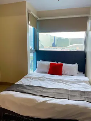 a bed with a blue headboard and two red pillows at Elegant 2 Bedroom Suite near Solaire, Okada in Manila
