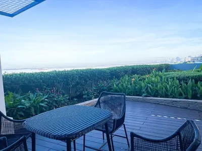a table and chairs on a patio with a view of the ocean at Elegant 2 Bedroom Suite near Solaire, Okada in Manila