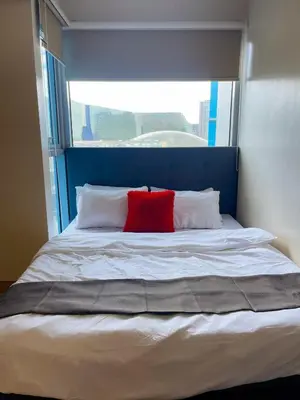 a bed with a blue headboard and a red pillow at Elegant 2 Bedroom Suite near Solaire, Okada in Manila