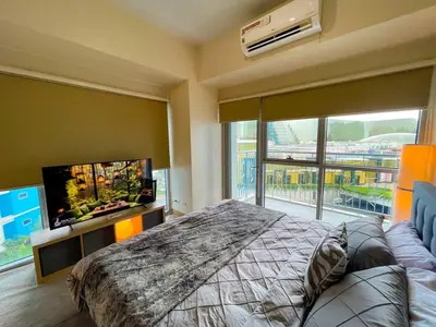 a bedroom with a large bed and a flat screen tv at Elegant 2 Bedroom Suite near Solaire, Okada in Manila