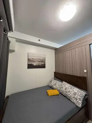 a bedroom with a bed with a wooden headboard at Entire 1 BR condo unit with balcony at MOA complex in Manila