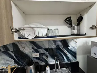 a shelf above a sink with plates and utensils at Entire 1 BR condo unit with balcony at MOA complex in Manila