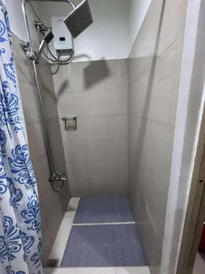 a bathroom with a shower with a blue shower curtain at Entire 1 BR condo unit with balcony at MOA complex in Manila
