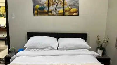 a bedroom with a bed with white sheets and a painting at T3 Airport Condo Escape by JM and Ian in Manila