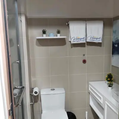 a bathroom with a toilet and a shower with towels at Homefort Twin Bed Suite - Red Residences Unit 2649 in Manila
