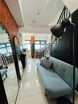 a living room with a blue couch and a staircase at Newly Renovated 2-storey Loft at Greenbelt 1 Near Legaspi Park in Manila