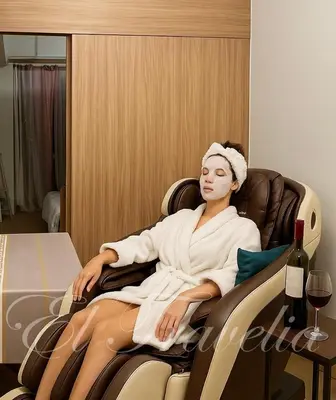 a woman sitting in a chair with a bottle of wine at 2 Bedroom with Massage Chair 15 minutes from NAIA in Manila