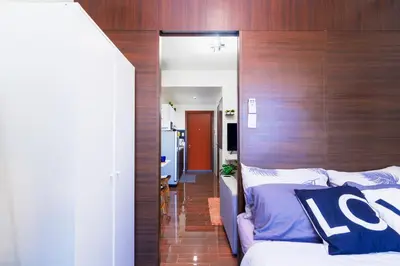 a room with a bed with a wooden head board at 1BR Staycation at AIR Residences Makati City in Manila