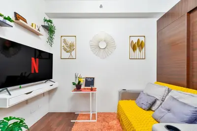 a living room with a yellow couch and a tv at 1BR Staycation at AIR Residences Makati City in Manila