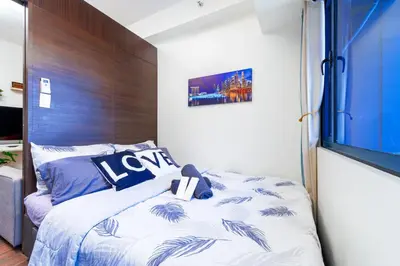 a bedroom with a bed and a large window at 1BR Staycation at AIR Residences Makati City in Manila