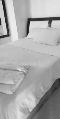 a bed with white sheets and pillows on it at Birch Tower - 1BR with balcony in Manila