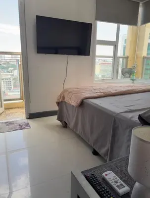 a bedroom with a bed and a flat screen tv at Birch Tower - 1BR with balcony in Manila