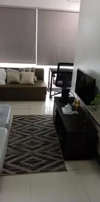 a living room with a couch and a table and a television at Birch Tower - 1BR with balcony in Manila