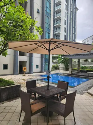 a table and chairs with an umbrella next to a pool at Staycation By JEM - Across NAIA T3 in Newport City in Manila